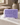 Savon de Marseille lavande avec de la mousse sur un lavabo dans une salle de bain sable, petit bouquet de lavande dans un pot