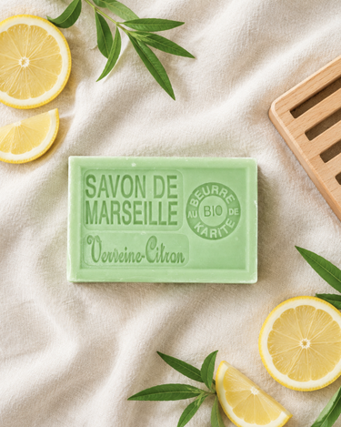 Savon de Marseille verveine-citron sur un lin crème, entouré de rondelles de citron, de verveine et d’un porte-savon en bois