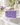 Savon de Marseille violette avec de la mousse sur un lavabo blanc, robinet ouvert, verre de violettes fraîches à côté